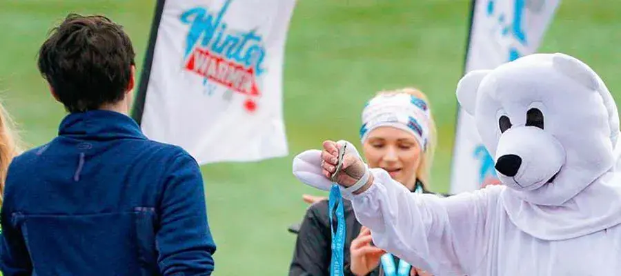 A polar bear mascot is handing out medals to Winter Run participants.