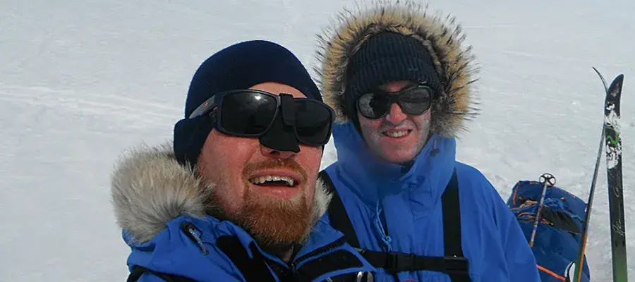 Darren Slevin and his friend Nathan Lumb pictured in blue winter jackets and skis on a snowy slope.