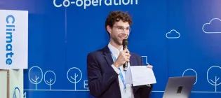 Max is holding a microphone moderating a panel at COP29.