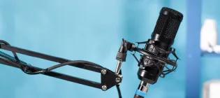 A black pod microphone photographed in front of blurred blue background.