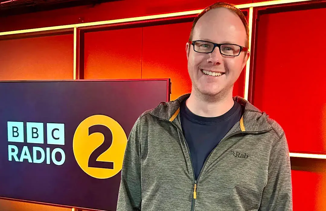 Tim Johns standing in front of the BBC Radio 2 logo.