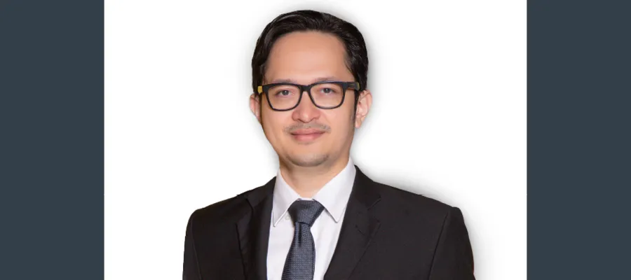 Portrait of Dr Handa Abidin on a grey background.