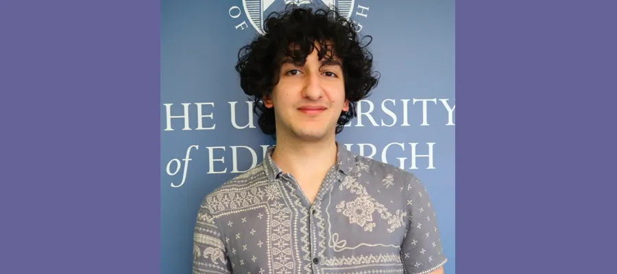 Ammir Barakat standing in front of the University of Edinburgh logo.