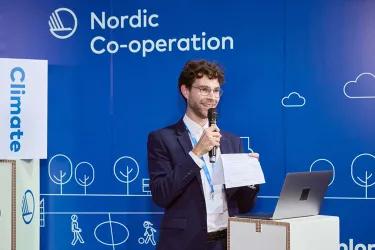 Max is holding a microphone moderating a panel at COP29.
