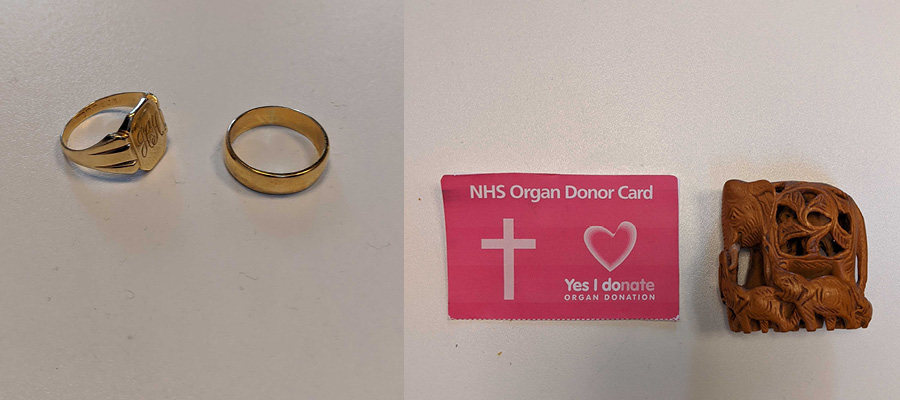 Gold signet ring and gold wedding ring, a pink donor card showing a crucifix and a small wooden carving of an elephant with two baby elephants.