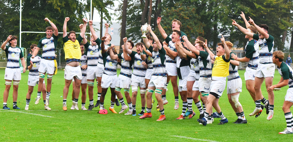 Rugby players jumping and celebrating on the pitch.