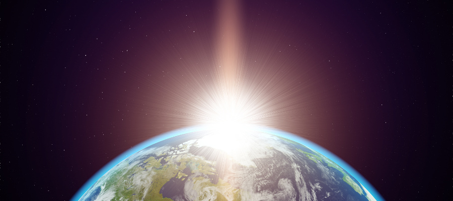 A view of the Earth from space with a flare of sunlight appearing on the horizon.
