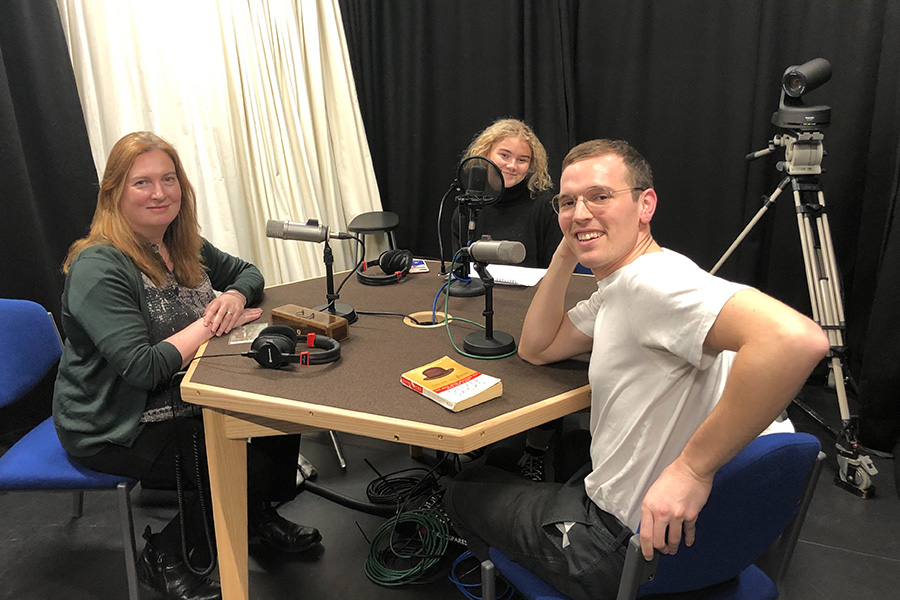 Melissa, Amalie and Max sitting around the recording studio table.