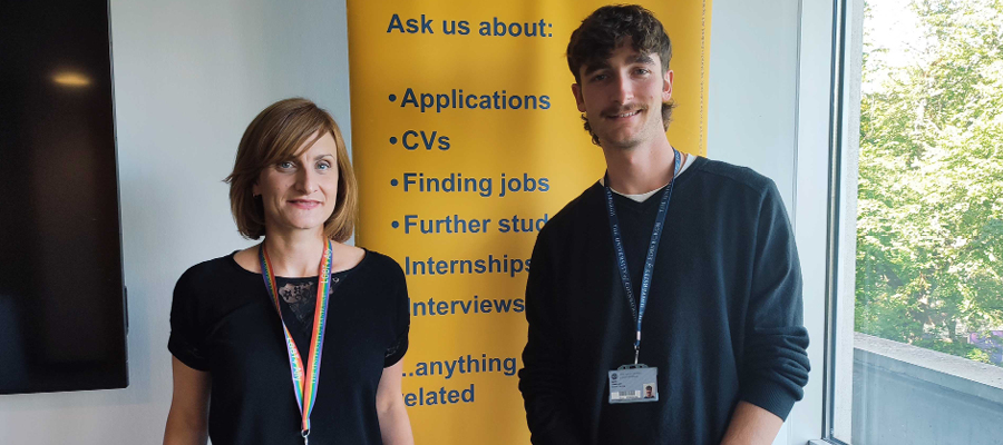 Matt O'Malley and Kirsten Roche smiling and standing in front of a Careers Service banner.